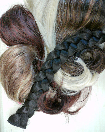 Langhaarperücken auf einem weißem Untergrund in verschiedenen Haarfarben und Macharten