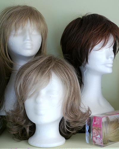 Drei Perücken mittlerer Haarlänge auf weißen Displays in der PErückenwerkstatt auf Rügen